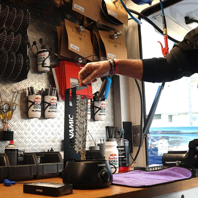 Mechanic from Red Bull - Bora - hansgrohe is waxing a chain with hot wax